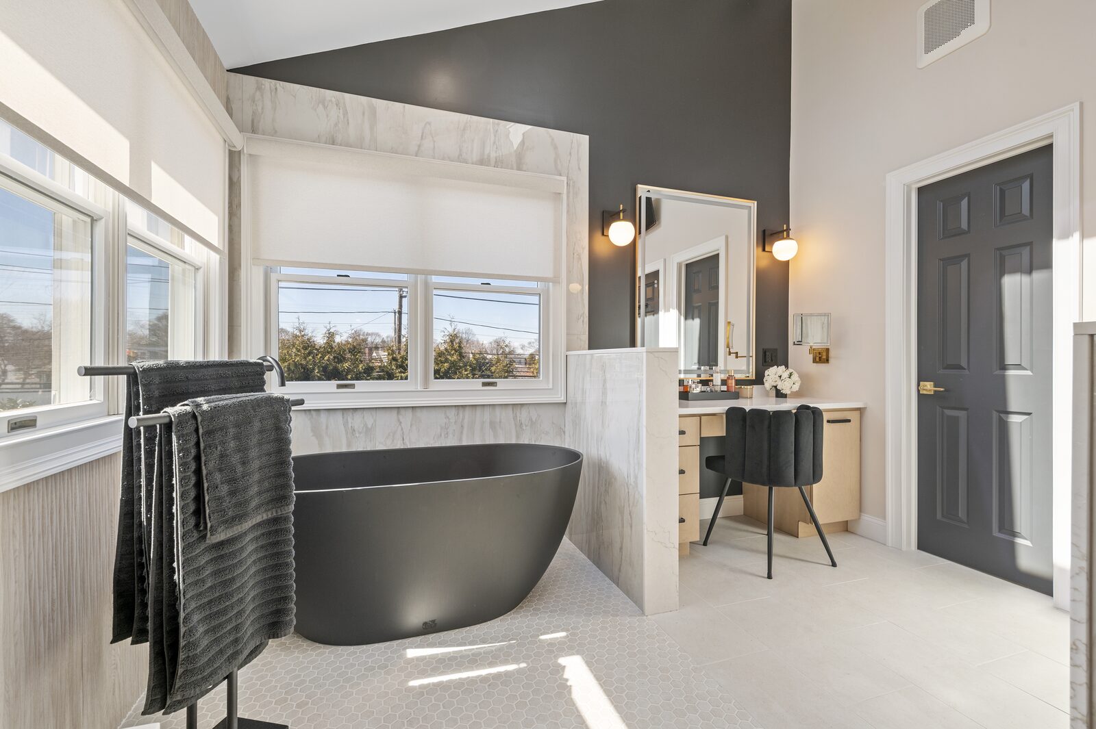 Black freestanding tub beneath a bathroom window