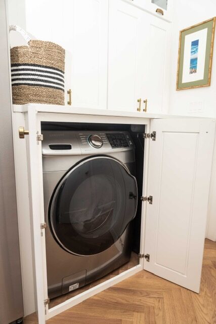 Washer and dryer concealed by white cabinetry